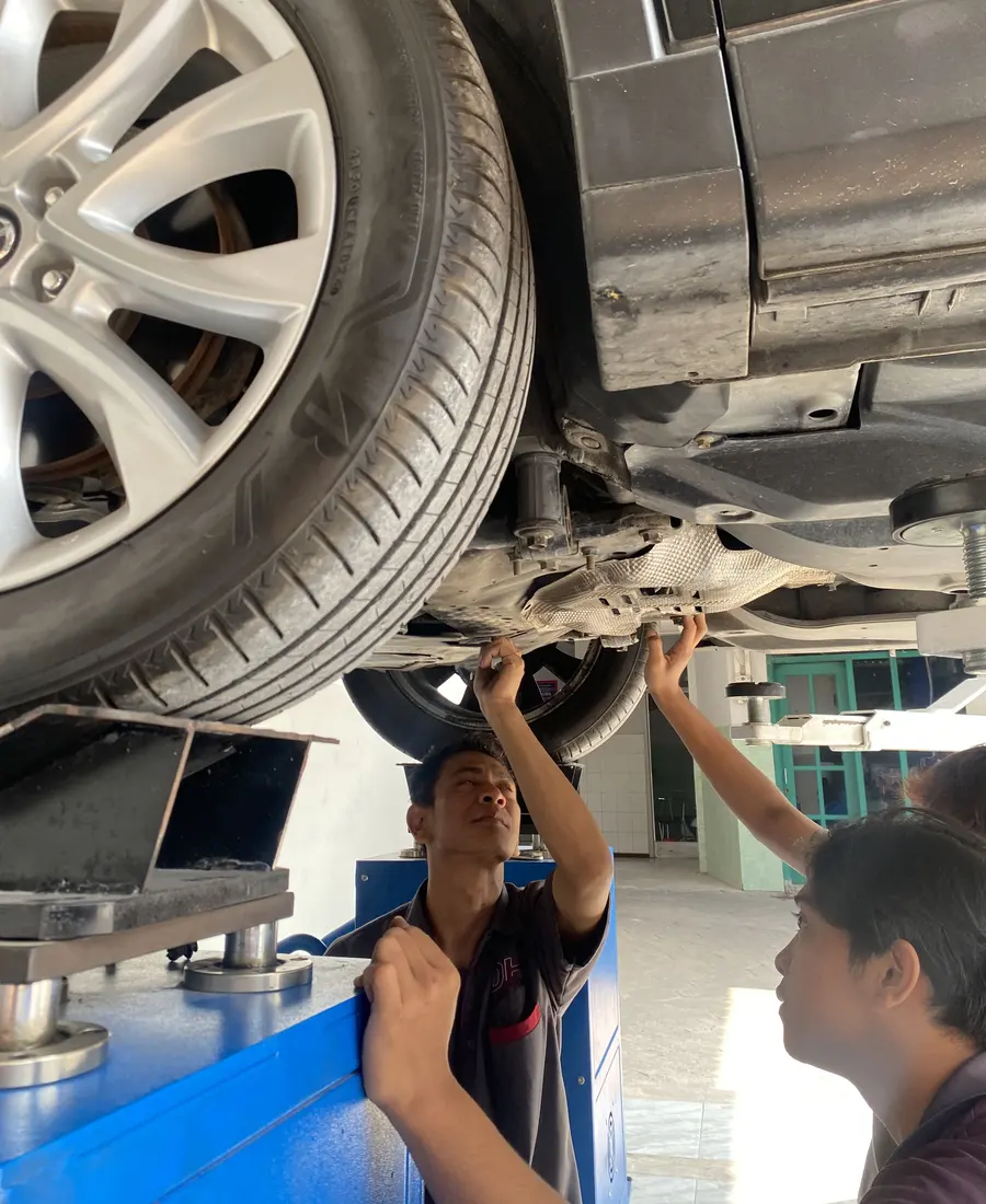 Mekanik memeriksa kaki-kaki dari kolong mobil