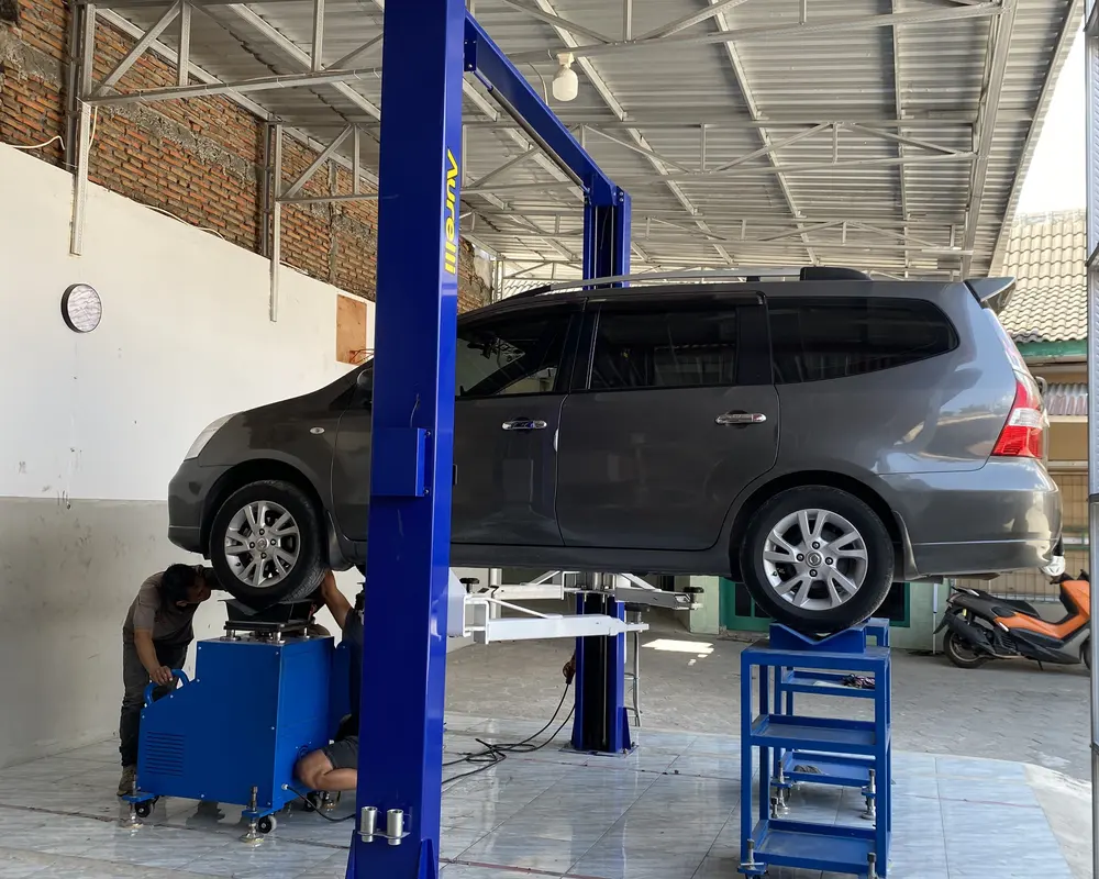 Mobil di atas lift dua tiang di bengkel DH Kaki-kaki