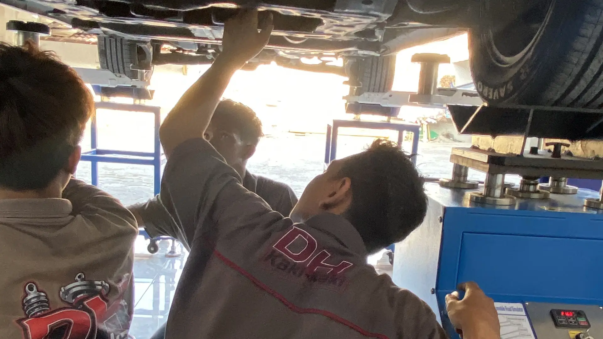Mekanik DH Kaki-kaki memeriksa kolong mobil di atas shaking machine